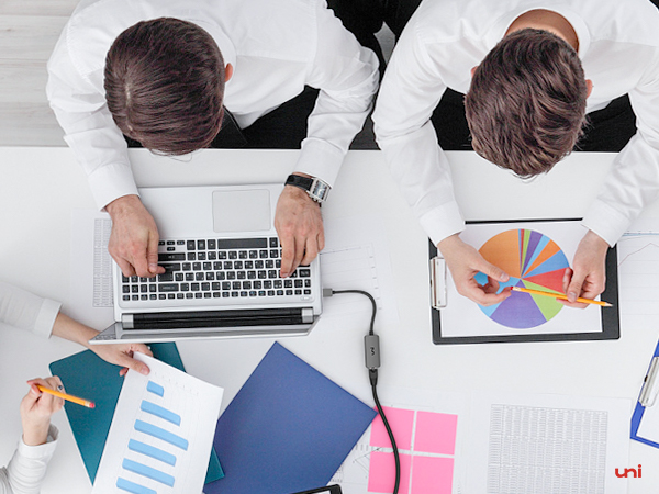 three people sitting at a table working on a laptop