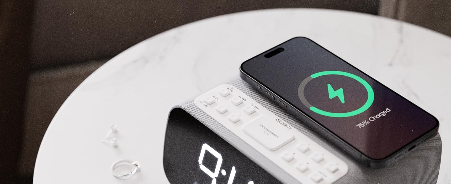 Smartphone showing 75 percent charging status on digital alarm clock with two rings bedside table
