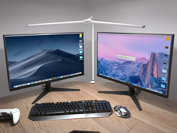 Dual-monitor setup with black keyboard and mouse on wooden desk, displaying landscape wallpapers on curved screens with LED desk lamp.