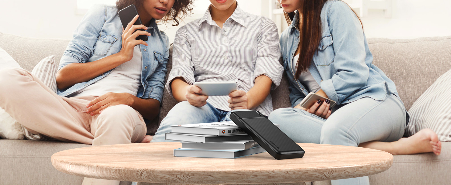 a group of people sitting around a table with a stack of books and a smartphone.
