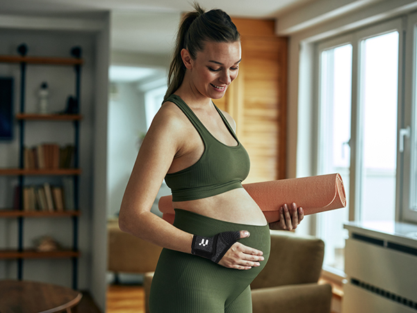 a pregnant woman holding a yoga mat