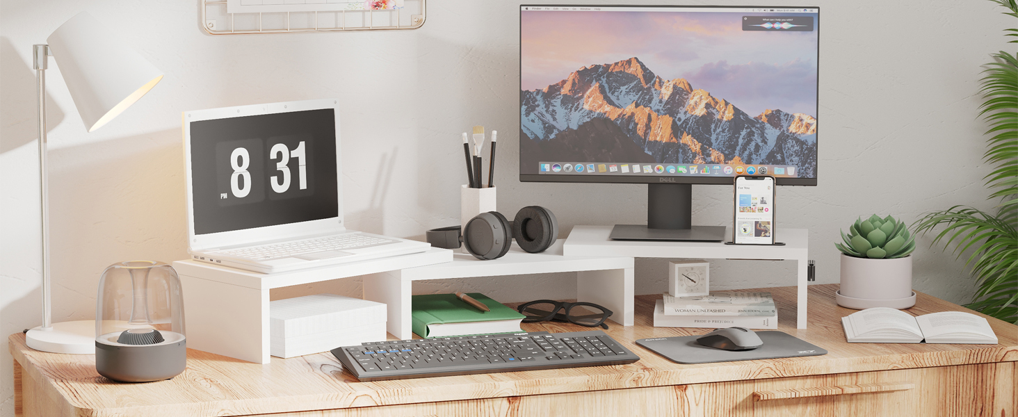Modern workspace setup with computer monitor, keyboard, digital clock, speakers, and various accessories on a wooden desk.
