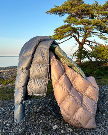 Blue, pink, and green Noora North ultralight down camping quilts on a chair, ideal for backpacking