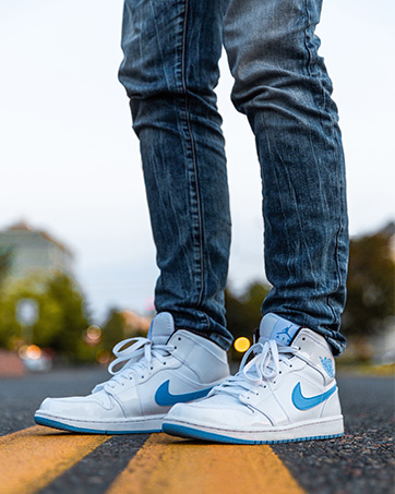 a close up of a person wearing blue jeans and a white nike air force 1 low.