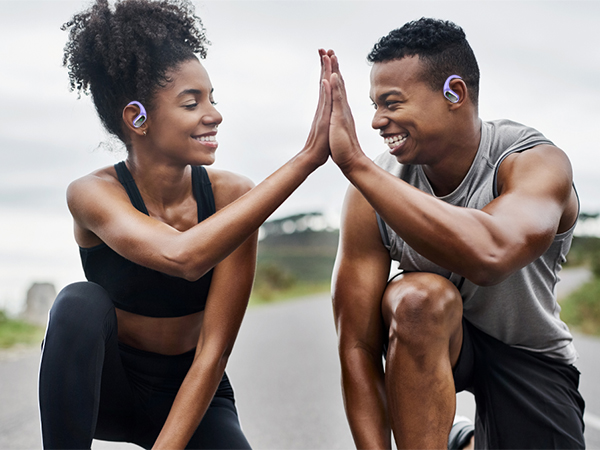 Two athletic individuals in workout attire giving each other a high five outdoors. They appear to be sharing a moment of camaraderie after exercise.