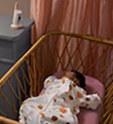 Philips Avent Premium Connected Baby Monitor sits on a table next to baby asleep