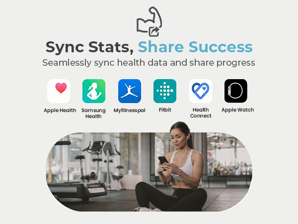 A woman sits cross-legged on the gym floor, checking her phone to share progress.