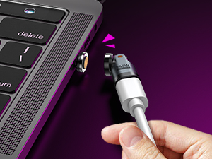 Close-up of a hand plugging a cable into an electronic device, likely a laptop or tablet. Purple background visible.