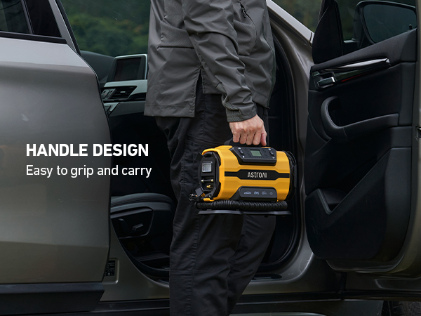 Yellow and black portable device with ergonomic handle design being carried near car door, showcasing grip and carrying functionality.