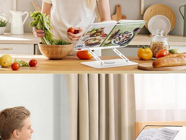 Tablet or device stand on kitchen counter with fresh ingredients spread around including tomatoes, bread, herbs in bowl, and citrus fruits. Kitchen setting with dishware visible in background.