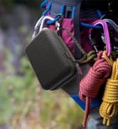 Close-up of outdoor gear including a black textured pouch, colorful ropes in pink, blue, and yellow, attached to a blue strap or bag.