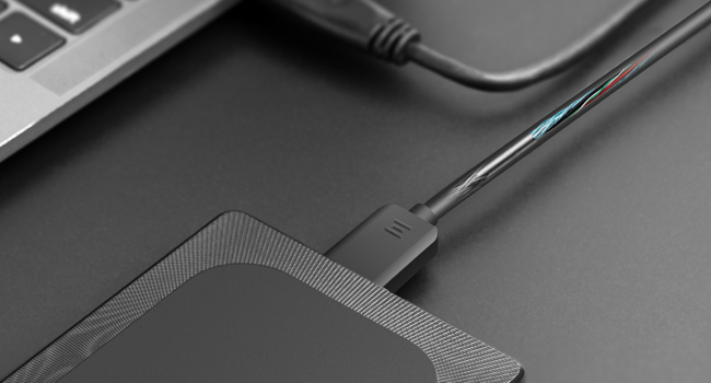 Close-up of black electronic cables or cords connected to a device, likely a charging or data transfer setup.