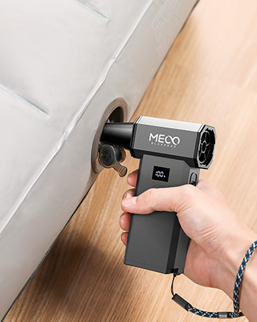 Handheld electric screwdriver in use, inserting screw into white surface. Device has digital display, MECO branding, and ergonomic grip. Compact design for tight spaces.