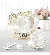 White porcelain tea set with gold trim, including cups, saucers, and spoons. Set includes a gold-colored display stand for hanging cups. Floral decor visible in background.