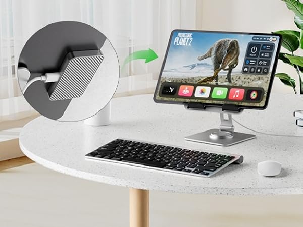 White speaker or device with circular mesh grille shown on white desk with keyboard and computer monitor displaying landscape. Arrow indicates product placement between peripherals.