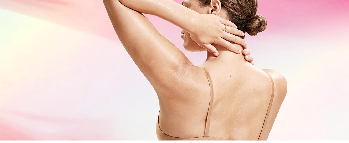 A woman touching her neck in front of a pink background