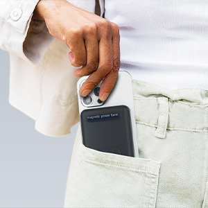 Hand holding small dark rectangular device or card case positioned in front jeans pocket, demonstrating compact size and portability.