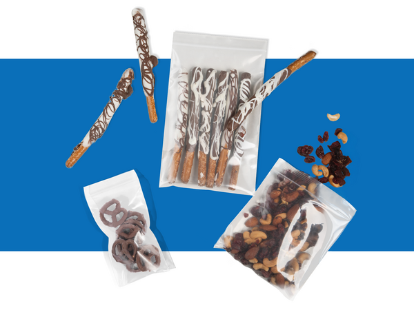 A flatlay of assorted chocolate pretzels and trail mix packaged in clear poly bags.