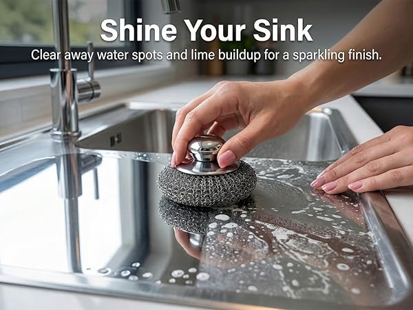 Metal sponge cleaning water spots and limescale from stainless steel kitchen sink.
