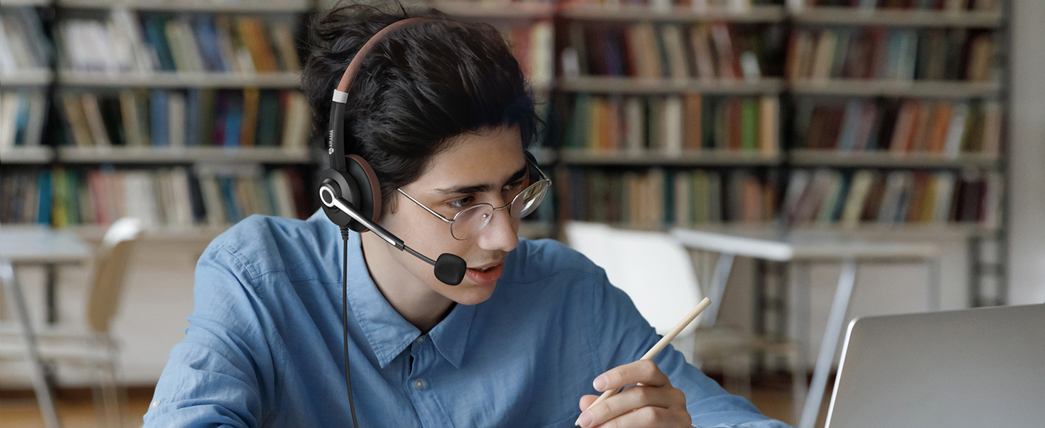 A boy wearing ARA700 wired headset is taking an online class in the library.