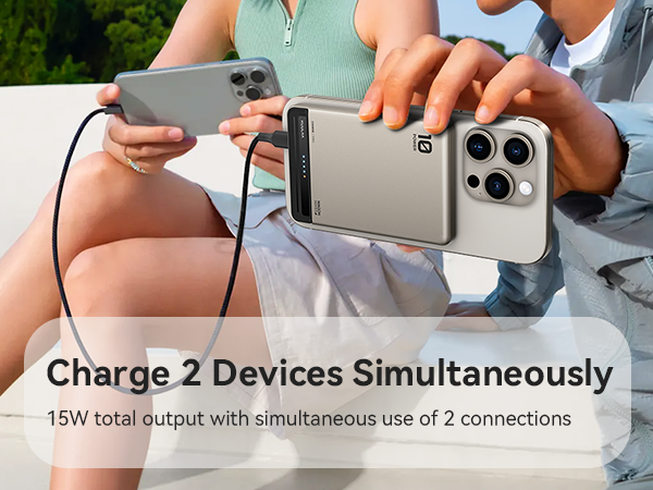Portable battery pack charging two smartphones simultaneously. Device is slim, rectangular, and has multiple ports. Text indicates 15W total output with 2 connections.