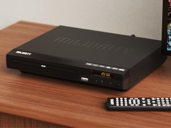 Majority region free dvd player on wooden shelf in living room. Display shows time