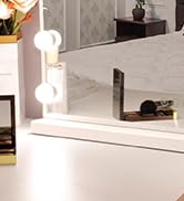 Partial view of a minimalist interior space with white walls and floor. A corner of furniture and circular wall lights are visible.