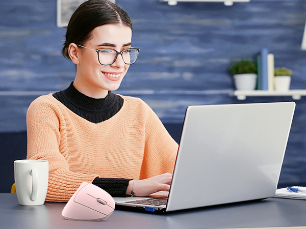 a woman sitting at a desk with a laptop and a mouse