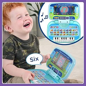 Boy laughs after pressing the 6 on the piano key. Toy laptop says: six!