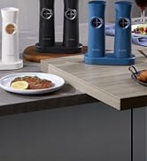 Collection of cylindrical dispensers in white, black, and blue colors arranged on a wooden surface, with matching pairs displayed on circular bases.