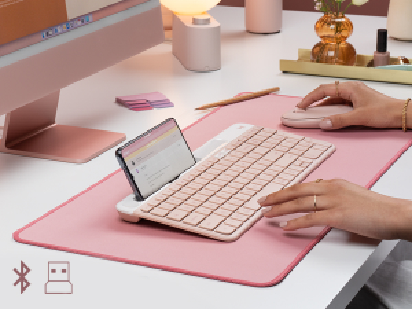 a woman using k585 slim wireless tenkeyless rose keyboard and m350 pebble shaped cordless pink mouse