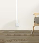 Modern minimalist interior with white walls and light wooden flooring. Wall-mounted shelf or ledge visible against plain backdrop.