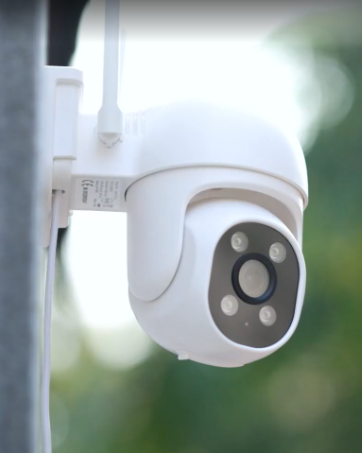 White outdoor security camera with dome-shaped design, featuring multiple LED lights and a central lens, mounted on a wall or ceiling.