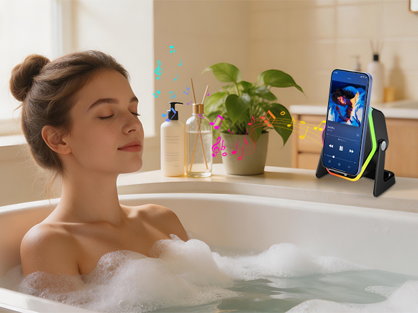 Bathroom scene showing smartphone mounted on stand near bathtub with indoor plant and bath products visible.