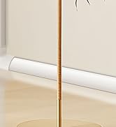 Tall gold-colored floor lamp with slim pole design and circular base, photographed against white wall and floor setting.