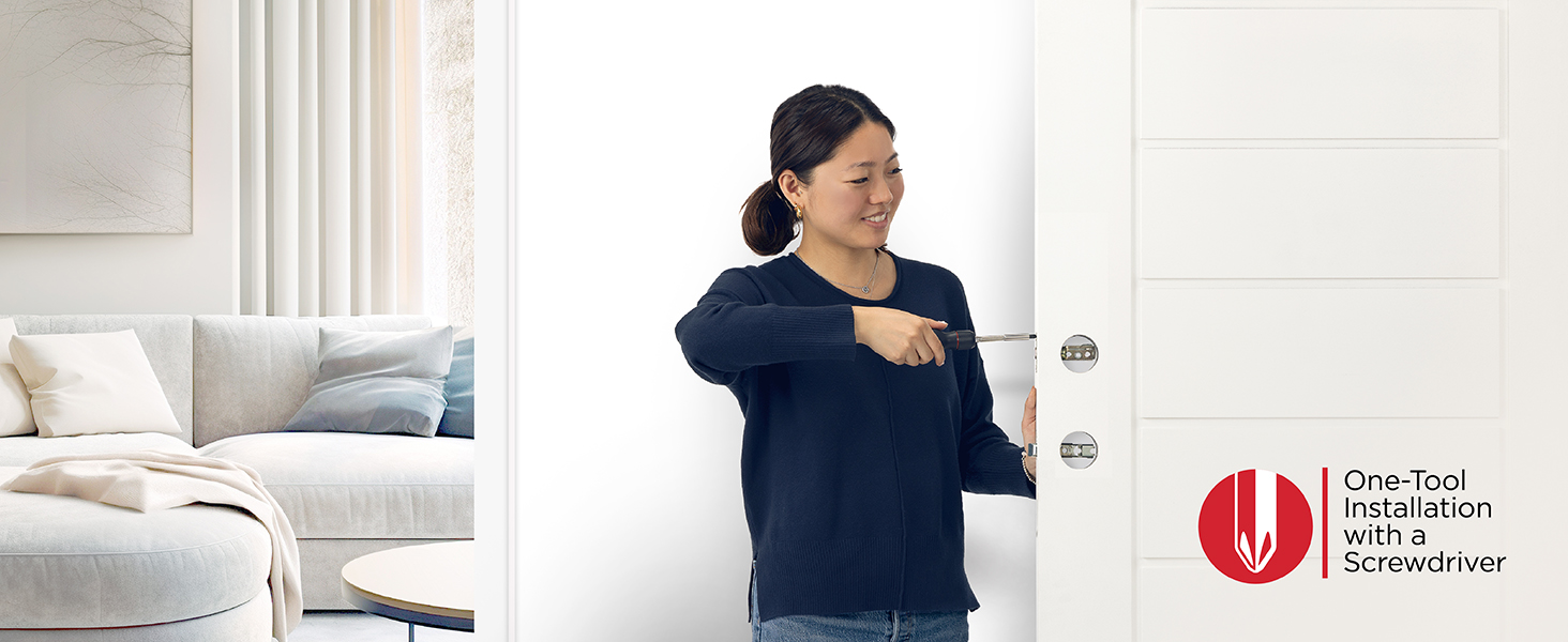 A smiling woman screwing in a door latch with a screwdriver.