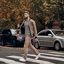 Casual outfit featuring tan bomber jacket, gray t-shirt, khaki pants and white sneakers, shown in autumn street setting with fallen leaves.