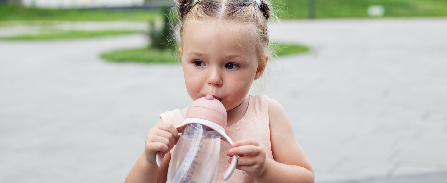 baby girl sipping out of a sippy cup outside