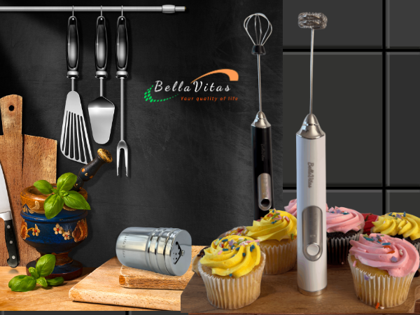 White and black milk frothers, cupcakes, cocoa shaker, utensils, and espresso on a kitchen board.