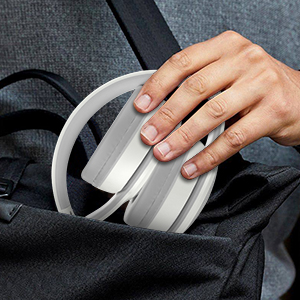 Close-up view of white over-ear headphones being held, showing the adjustable headband and plush ear cushions against a dark fabric background.