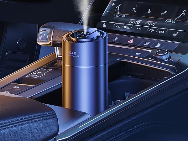 Metallic blue car humidifier or diffuser placed in vehicle cup holder, with mist emerging from top opening.