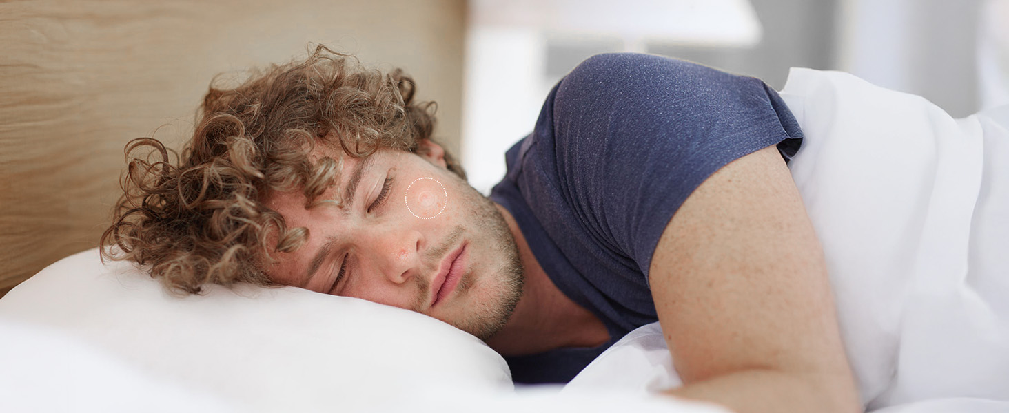 Person with curly hair sleeping on white pillow wearing dark blue pillow cover, demonstrating comfort and sleep positioning.