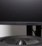 partial view of a speaker cone and a desktop computer screen
