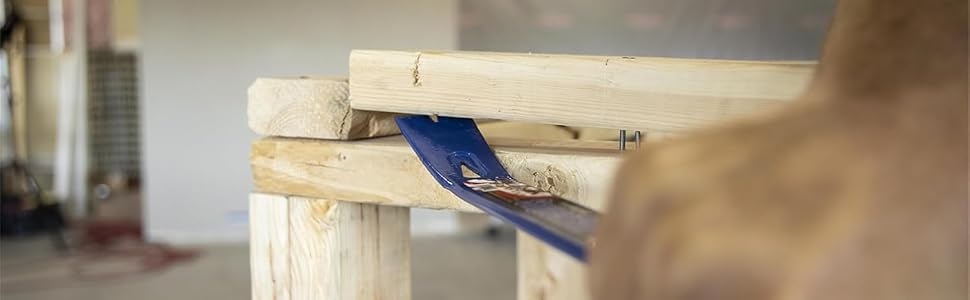 Close-up of a blue wooden clothespin or clamp being attached to a light-colored wooden surface.