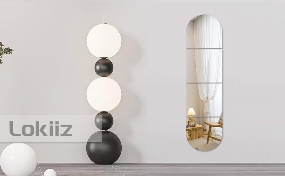 Modern decor set featuring stacked spherical floor lamp with alternating black and white orbs, alongside oval-shaped wall mirror.