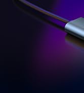 Close-up of a thin, metallic object with a purple glow emanating from one end against a dark background.