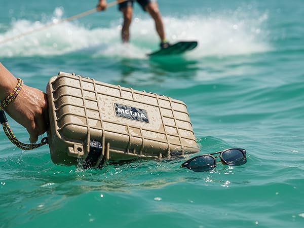 Waterproof protective case being held over water with surfing activity in background. Case appears rugged and designed for water resistance.