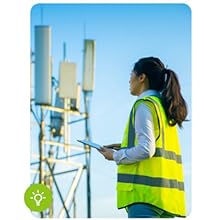 Female engineer in neon vest looking at cell tower