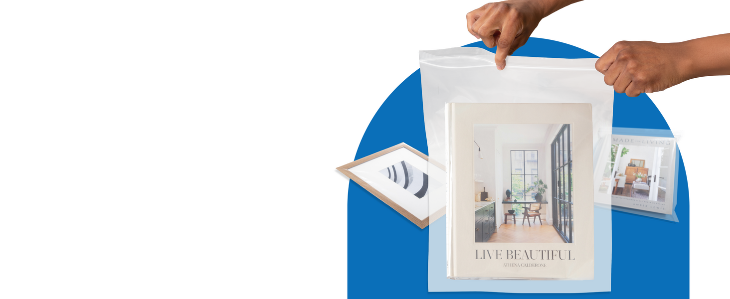 A pair of hands zip a bag shut with a book inside. Another book and picture frame lay behind it.