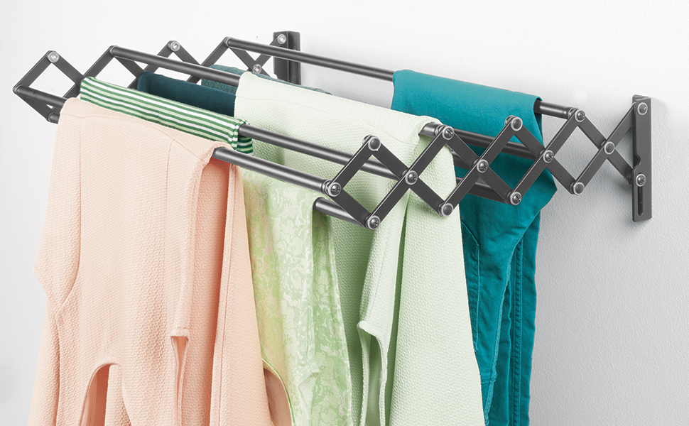 black wall mounted expandable drying rack holding laundry on a white wall